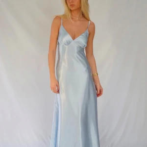 Ljusblå långklänning i satin - Elegant ljusblå långklänning i satin med smala axelband och v-ringad design från ByStina. Perfekt för bal och andra event. En av plastcirklarna gick sönder under min bal så jag fixade de snabbt med ett örhängen. Skriv för fler bilder, pris kan diskuteras 🌸