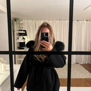 Svart kappa med pälskrage - Använd ett fåtal gånger. Är i ett väldigt bra skick. Storlek S.   Äkta päls. Går att ta av och på pälsen. Ull/kashmir