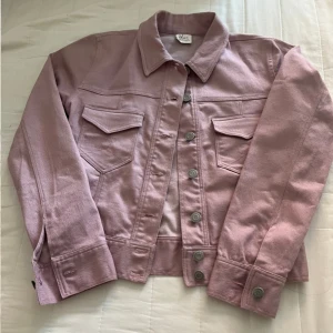 Rosa jeansjacka - Säljer en superfin ny rosa glittrig jeansjacka från Zara. Den har en klassisk krage och knappar framtill. Jackan har två bröstfickor med lock och är i en snygg croppad stil. Perfekt för vår och sommar!