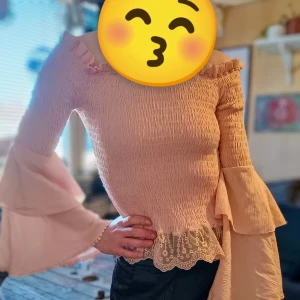 Romantisk ljusrosa spetströja med volangdetaljer - Super romantisk stil i 1700-1800-tals anda.Säljer en superfin ljusrosa blus med spets och volangdetaljer. Tröjan har långa ärmar och en söt volangkant vid halsen och nederdelen. Perfekt för vårens och sommarens fester! 💖