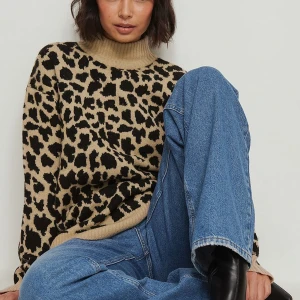 Leopardmönstrad stickad polotröja - Säljer en supercool leopardmönstrad stickad polotröja. Den är perfekt för höst och vinter med sin mysiga och varma känsla. Tröjan har långa ärmar och en bekväm polokrage. Den är i en snygg beige och svart färgkombination som verkligen sticker ut. Perfekt för att hålla stilen när det blir kallare!