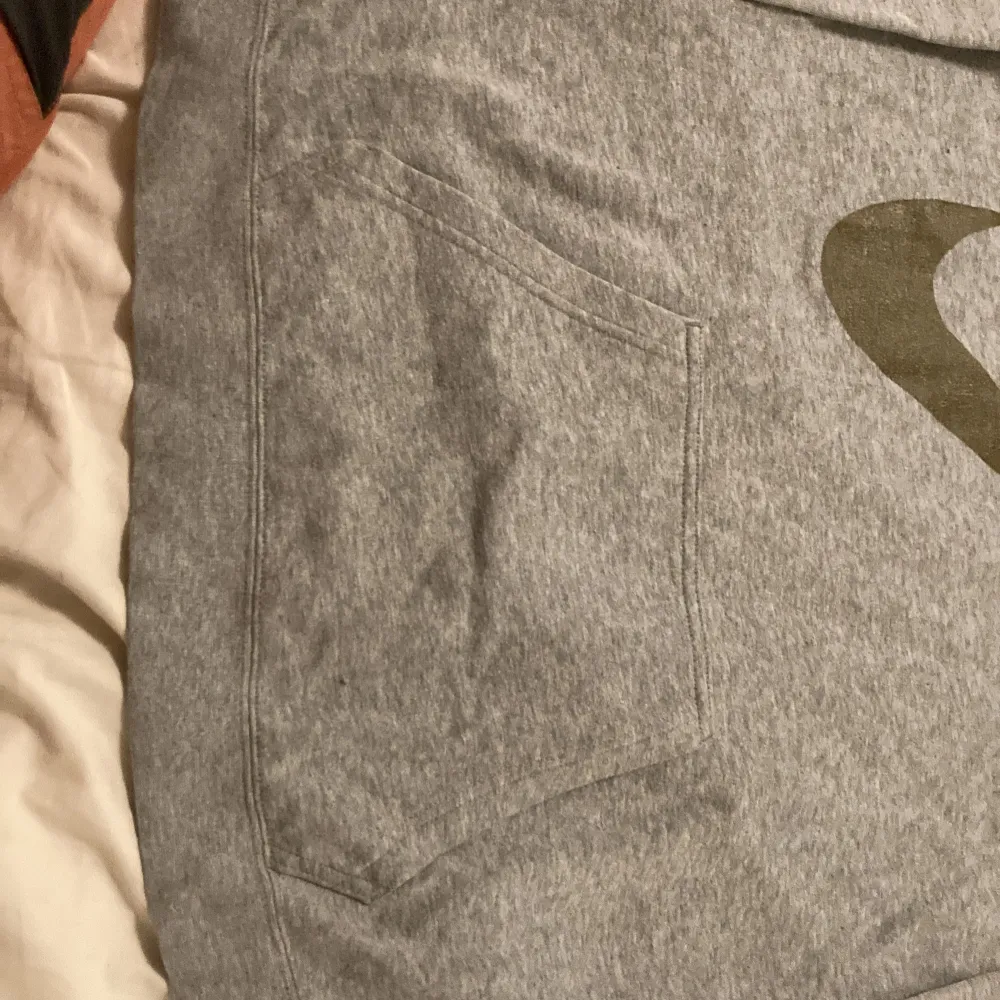 Säljer en grå hoodie från Nike i storlek 156-166 cm, perfekt för tonåringar. Den har en stor Nike-logga på framsidan och en praktisk magficka. Tröjan är i mjukt material och har långa ärmar med ribbade muddar. Perfekt för både vardag och träning!. Tröjor & Koftor.