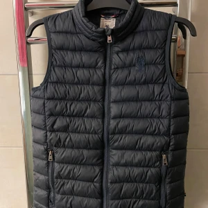 Polo assn väst - Skitsnygg väst, skick bra bara att det finns ett lagat hål på ryggen som inte syns vid användning, pris 299 kan även diskuteras vid snabbaffär! Passar dig runt 170