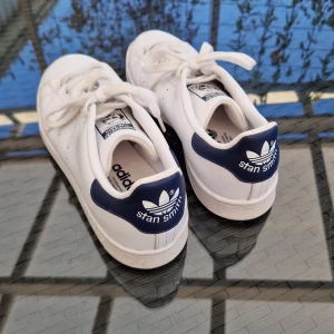 42 | Adidas Stan Smith Sneakers  - Vita / mörkblå Adidas Stan Smith Sneakers. Storlek 42. Bara använda några gånger så väldigt fint skick. Hör av er om ni har några frågor :)