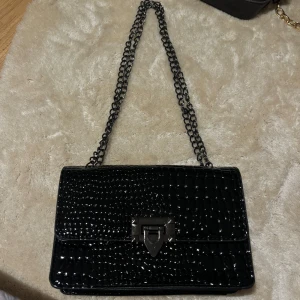 väska - Väldigt elegant väska med svart ormskin mönster, helt nyskick men lite gammal. 