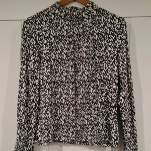 Svartvit mönstrad långärmad blus - Säljer en snygg svartvit mönstrad blus med långa ärmar. Passar bra till jeans eller kjol. S men sitter löst så passar nog M också.