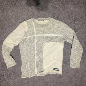 Grå långärmad tröja från Cipo&baxx - Säljer en unik grå långärmad tröja från Cipo&baxx. Den har ett coolt patchwork mönster med olika grå nyanser och råa kanter för en edgy look. Perfekt för höst och vår! 🖤