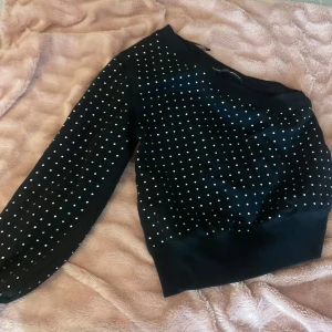 Svart prickig tröja - Säljer en snygg svart tröja med vita prickar. Den har långa ärmar och en bekväm passform. Perfekt för både vardag och festliga tillfällen. Tröjan är i bra skick och redo för en ny ägare!
