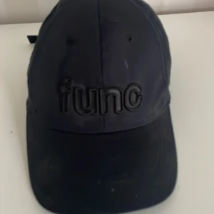 Svart keps från Func - Säljer en svart keps från Func. Den har en broderad logga framtill och justerbart spänne bak. Perfekt för vardagsbruk eller träning. Kepsen är i bra skick och passar de flesta tack vare den justerbara passformen.