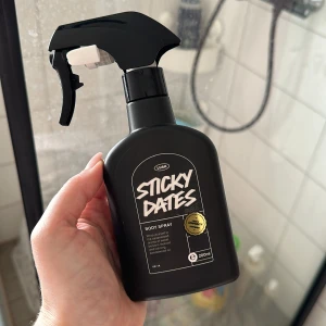 Sticky Dates Body Spray från Lush - Säljer en 200 ml flaska av Lush Sticky Dates Body Spray. Den har en cool svart design med en praktisk sprayfunktion. Doften är karamelliserad med inslag av dadlar och sandelträ. Perfekt för att fräscha upp sig med en söt och varm doft. Passar både vardag och speciella tillfällen! Är använd fåtal gånger. 