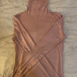 Polotröja - Säljer en superfin rosa/ beige polotröja i mjukt och stretchigt material. Perfekt för kyliga dagar med sin långa ärmar och sköna passform. Tröjan är i bra skick. 