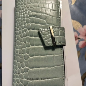 Ideal of Sweden fodral - Ett mingrönt frodral som är använt men fint skick  + tillhörande skal i svart som är oanvänt. Till iPhone 12. Nypris 399kr