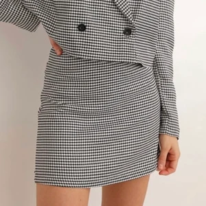 Hundtandsmönstrad minikjol Chiquelle - Minikjol i smått hundtandsmönster från Chiquelle med dragkedja baktill. Endast provad och aldeig använd då den är lite för stor. Nypris 379 kr.