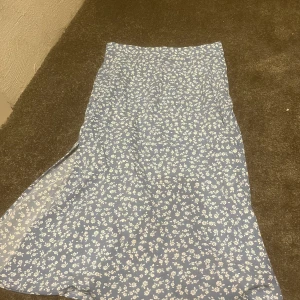 Kjol me slit  - En jätte fin blå kjol me vita blommor me slit längst ner 