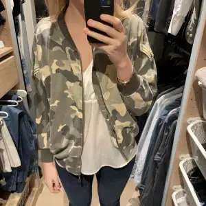 Jacka i tyg med camouflage och detaljer 