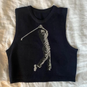 Stickad väst med brodyr - Stickad mörkblå väst med silvrigt broderad golfgubbe, mycket söt och unik. Obs, spegeln är smutsig och inte plagget.
