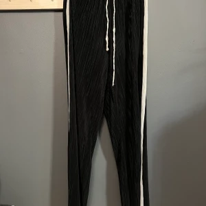 Byxor från Gina tricot - Svarta byxor med vita ränder på sidorna från Gina tricot. Väldigt sköna byxor mad snörning. Storlek xs, fint skick. 