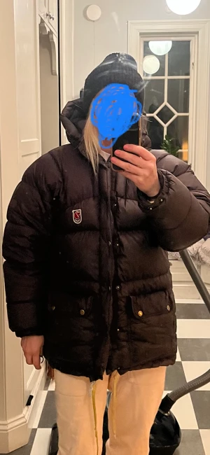 Fjällräven  - Säljer min fina mörkbruna Fjällräven unisex expedition i strl xxxs (stor i strl) motsvarar strl S. Fint skick. Detta är den äldre modellen med mycket dun i. En liten lagning på ena armen med laga lappen. Kemtvättad en gång. Finns i Jonsered. Frakt ingår. 