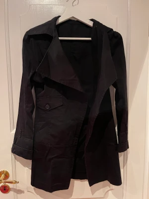 Svart Trench Coat  - Svart trench coat, står inte storlek men gissar på s/m. 