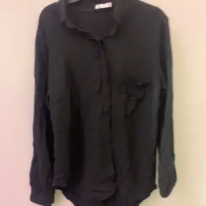 en svart skjorta/blus,perfekt till sommaren med en ficka på bröstet