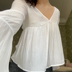 vit blus - Säljer denna v-neck blus med utsvängningar både i armarna och på överkroppen. Superfin knutning och spetsmönster på övre ryggen! Tunt material som ändå inte syns igenom om man har rätt bh under. Pris diskuterbart🥰