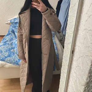 Nelly Quiltad Kappa - Quiltad kappa från Nelly som är väldigt sparsamt använd och således i toppskick! Grå-brun/minkfärgad och passar perfekt till våren. Passar mig som vanligtvis har strl XS men passar nog fint även för dig i strl S. Jag är 1.64 cm och jackan räcker till nedre halvan av vaderna. 