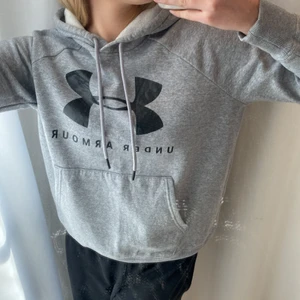 Hoodie Under Armour - Grå hoodie från Under Armour. Använd endast fåtal gånger. Bra skick. Logo i svart på framsidan. Bra till både träning och vanligt. Mysig inuti.