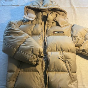 Jacka JNS sportswear - Superfin beige dunjacka i storlek 150, den är ganska kort i armarna. Annars jättebra skick. Kan skickas och då får köparen står för frakten. Annars finns den i Piteå.😊💕