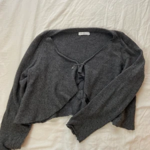 mysig kofta bolero - Jättesöt liten mörkgrå bolero/kofta, stängs med en dekorativ säkerhetsnål. Står inte storlek men uppskattas till S, jag på bilden har XS🤎  Möts i slussen eller postas, köp nu är på :)