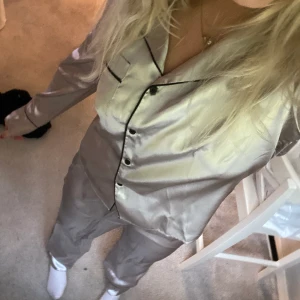 Satin Pyjamas - Säljer en helt oanvänd satinpyjamas från booho i en snygg silvrig färg med svarta detaljsömmar!😍 strl 38 men passar även mindre🫶🏼