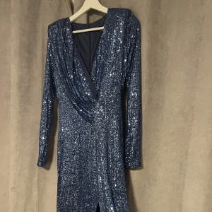 Balklänning  - En fin blå klänning som aldrig används med prislapp kvar! Ordinarie pris var 1000 kr inklusive shipping samt taxes då den är från USA. Den har en fin blå färg med helt otroliga paljetter, en split vid vänstra ben och har en super fin passform!