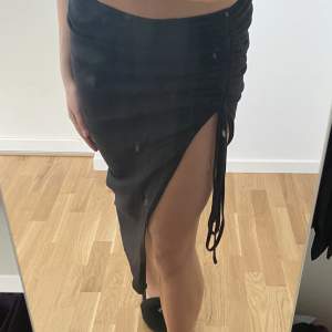 Lågmidjad  lite längre svart kjol med rynkad detalj. Superfin och jätteskön.