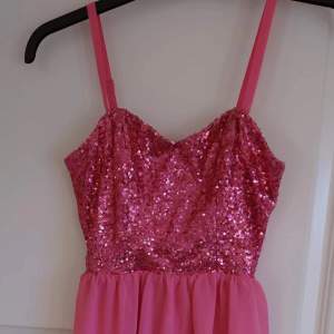 Härligt rosa klänning med paljetter upptill och med chiffongunderdel. Avtagbara axelband. Sparsamt använd så i mycket fint skick 