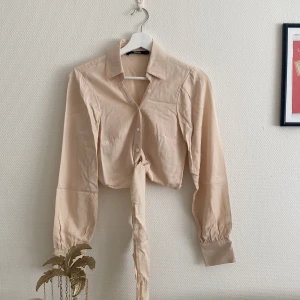 Beige blus - Använd 1 gång, perfekt skick! Jättemjukt & bekvämt material. Går att knyta ”banden” i ryggen eller som rosett fram!