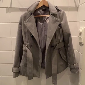 Kort kappa  - Säljer nu min superfina gråa korta kappa i jättebra skick! Jag är 171 cm å den e varken för lång elr för kort🥰älskar alla detaljer! Den är köpt second hand så går inte att få tag på längre! Motsvarar en storlek S!