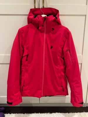 Peak performance skidjacka  - Rosaröd skidjacka från Peak performance i storlek Medium. Jackans namn är "Style W anima J". Använd i två säsonger. Den har ett litet hål och en liten fläck längst ner på höger framsida (se sista bilden). I övrigt är den i fint skick. Köpt för ca 3000 kr.