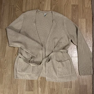 Nelly kofta - Super fin stickad kofta i från Nelly i fint material, använd ca 2 gånger. Den har ganska hög slits på sidan, två fickor och ett band att knyta i midjan. Storlek M🫶🏼