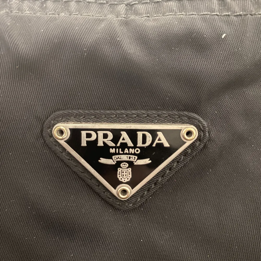 Vintage Prada väska som är trasig i dragkedjan, (se bild). Den går att stänga men är inte helt tät. Går nog att byta ut. Lyssnar på bud.. Väskor.