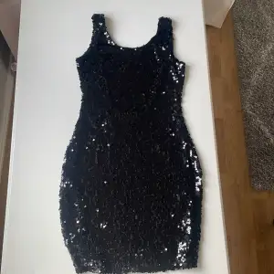 Kroppsydd paliett klänning i svart öppen rygg med ett band ,nästan helt oanvänd,klänningen är i storlek 34 (XS) är dock som en (S)