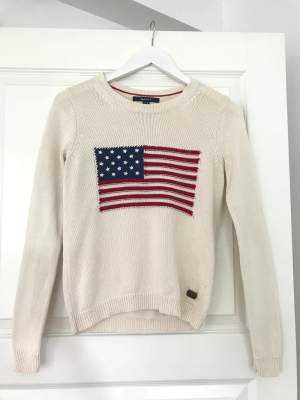 Krämvit stickad tröja från Gant med USA flagga. Tillverkad i 100 % bomull. Jättefint skick då den är ytterst lite använd.  Storlek: xs Nypris: 1399 kr Fraktavgiften står köparen för!💫
