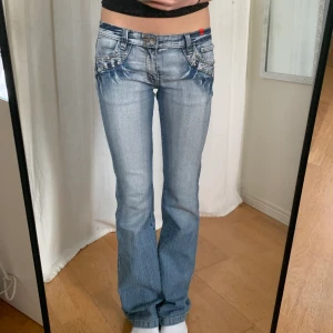 2000s jeans - 2000s jeans med snyggaste detaljerna fram och bak!! Många rhinestones har ramlat av på bakfickorna tyvärr :( midjemått:77+stretch innerbenslängd:84,5