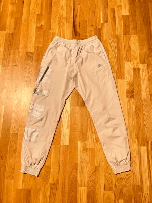 Nike nylon trackpants - Vita/creamvita Nike byxor av nylon/polyester. Köpta på caliroots för retail: 700kr säljer nu för 250kr. Inga flaws, endast använda ett par gånger.