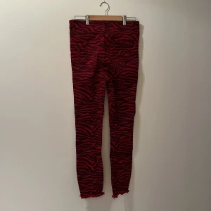 Zebra röda tights i denim, halvlånga ben. Fransavslut. - Stretchig byxa i röd zebramönstrad denim, sköna!