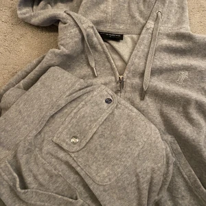 Juicy couture set - Säljer mitt juicy couture set i färgen grey marl. Tröjan i storlek S och byxorna i storlek Xs. Fint skick förutom att ena metallbiten på snöret har trillat av. Skriv för fler bilder. Säljer endast som ett set🫶🏻