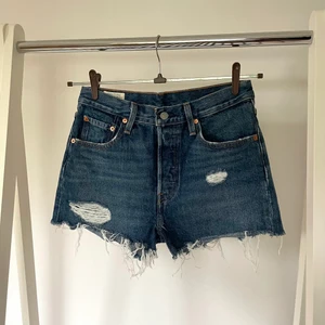 501 Levi’s shorts - Ett par snygga mörkblå levis shorts med slitningar runt benen och på fickorna. Slutar i benen så att rumpan inte hänger utanför! Använt sparsamt.