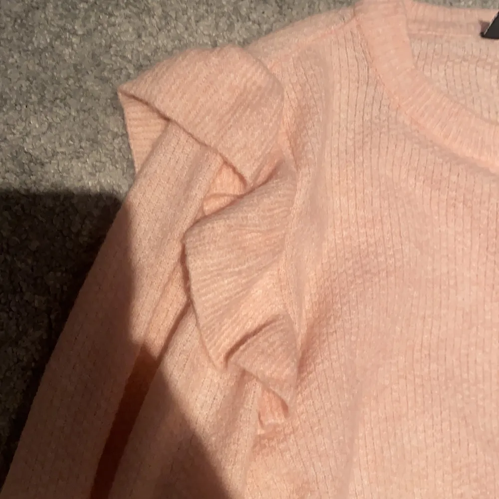 En rosa stickad tröja med volanger på armarna som aldrig är använd. Strl XS . Pris:80 kr. Stickat.