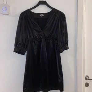 Svart festklänning - Svart midi/kort klänning från BikBok, glansigt och mjukt material, lite puffärmad. nytt skick