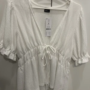 Vit blus/topp från Gina tricot, oanvänd.  - Blus med knytning som är oanvänd. Storlek M