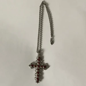 Silverfärgat kors halsband med röda strassar - I gott skick men dm:a gärna vid frågor angående storleken eller närmare bild på utseendet! Köparen står för frakt