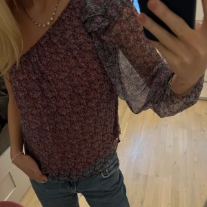 One shoulder blus - Jättefin blommig one shoulder blus! ”See trough” på baksidan! Köpt i en butik i Spanien!
